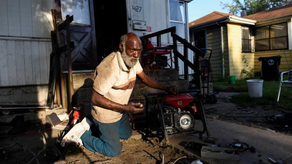 Anthony Lewis repairs a generator at his home while coping without electricity, as thousands of residents remain without power more than a week after severe storms struck Gary, Indiana.