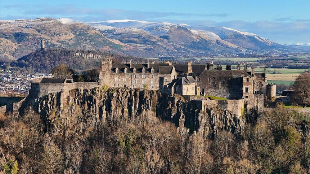 Stirling castle with the Wallace monument and snowy Ochil hills in the background.