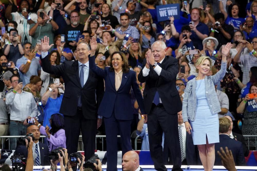 Doug Emhoff, Kamala Harris, Tim Walz and Gwen Walz wave at a crowd