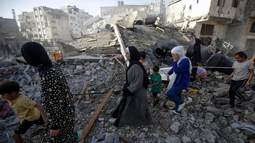 Family members inspect the rubble of their former home following an air strike during an Israeli military operation in Gaza City