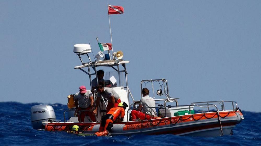 Diver hanging on to side of orange boat