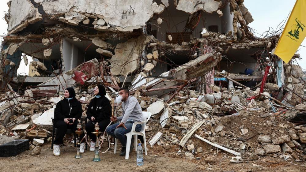 Returning residents sit at a damaged site, as Israeli troops withdrew from most of south Lebanon, in the southern Lebanese village of Kfar Kila, Lebanon,