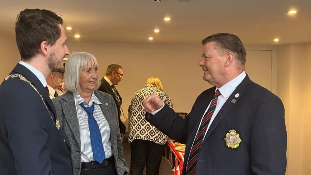 Thomas Murray, Dr Lori Boul and councillor Kevin Foster stand talking to each other in a room