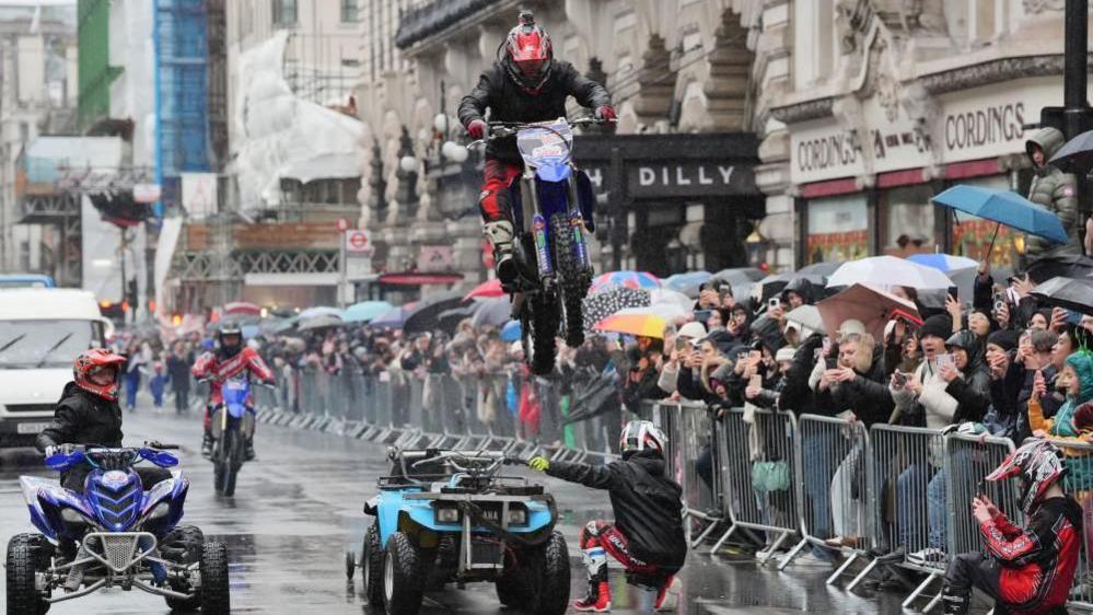 A motorcyclist performing a stunt during a parade in central London