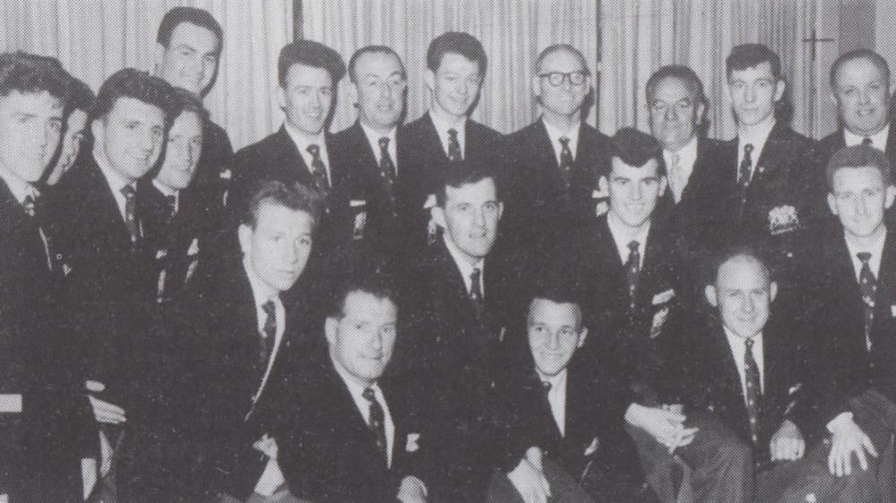 A black and white image of the 1960 Glenavon FC Irish League championship winning squad. They are looking at the camera and are wearing black suits, white shirts and dark ties.