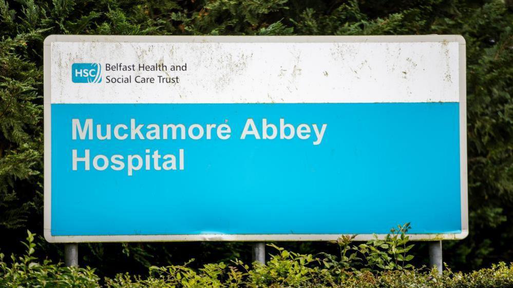 A blue sign that says Muckamore Abbey Hospital