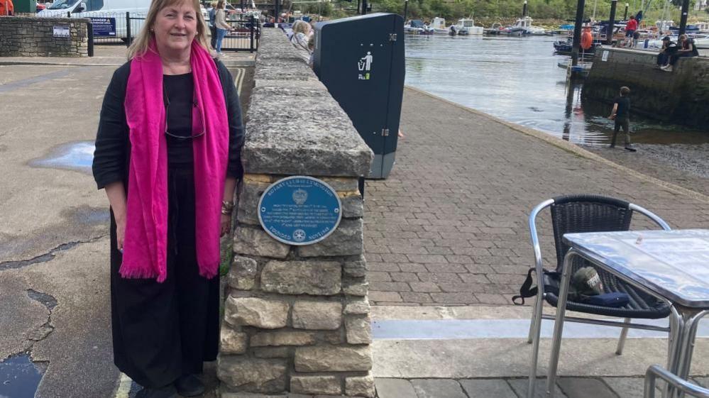 Jacqui England standing next to plaque