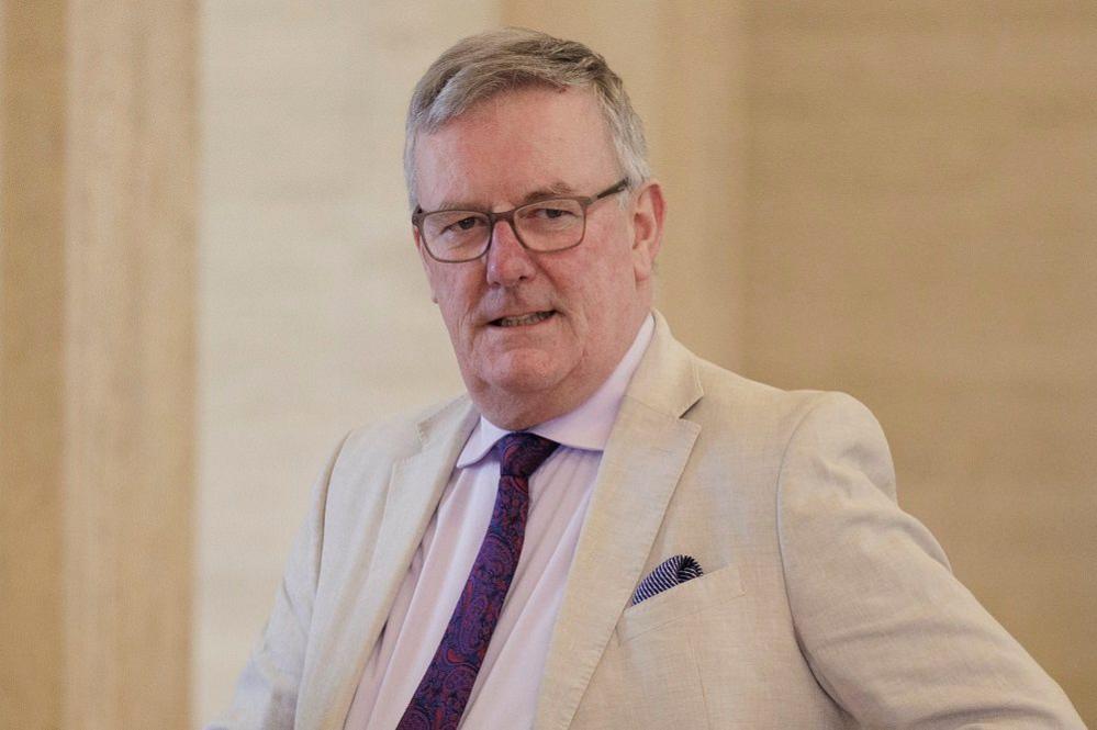 Mike Nesbitt in beige suit pink shirt and patterned purple tie