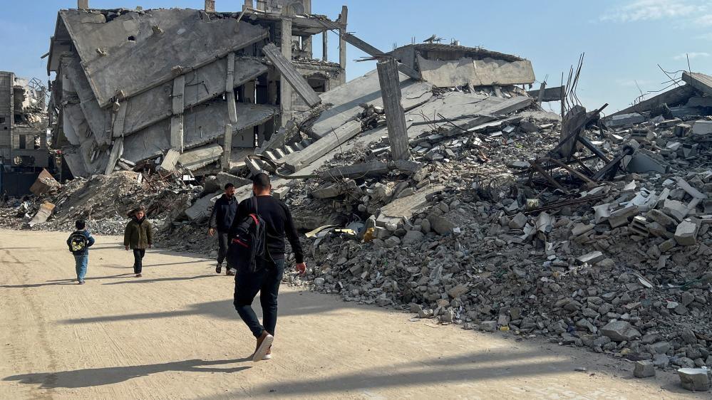 Palestinians walk past the rubble of destroyed houses, amid a ceasefire between Israel and Hamas, in Khan Younis in the southern Gaza Strip