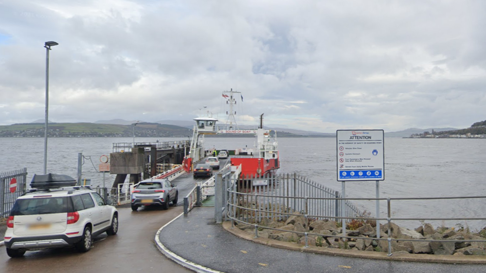 Cars driving onboard a red and white ferry. The River Clyde is in the foreground as well as some a health and safety sign