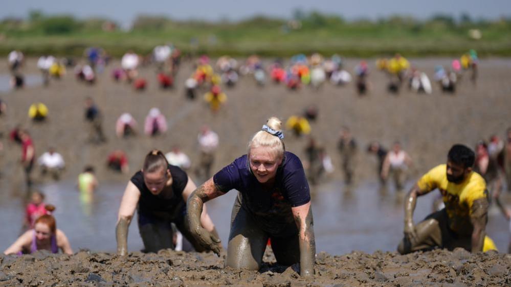 Competitors take part in the annual Maldon Mud Race, a charity event to race across the bed of the River Blackwater in Maldon, Essex