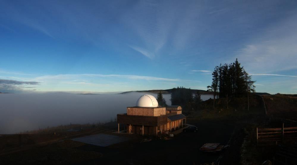 The dome of an observatory is visible above the most and below a clear blue sky