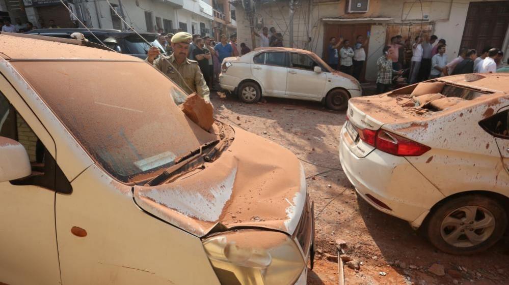 People gather around damaged vehicles and houses after shelling, at Jammu town in Indian-administered Kashmir on 10 May 2025