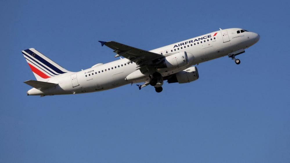 Air France Airbus A320 airborne above Spain shortly after take-off with red and blue tail livery and white fuselage with Air France logo. The undercarriage is still down.