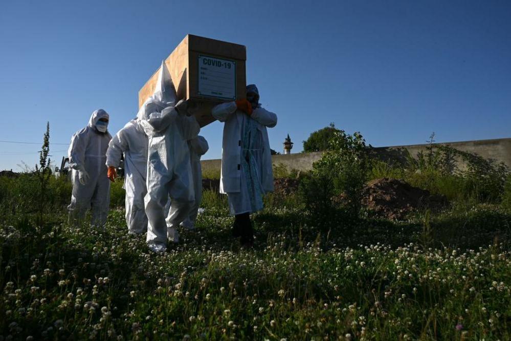 Relatives wearing Personal Protective Equipment (PPE) carry the coffin of a woman, who died from the COVID-19 coronavirus, before her burial at a graveyard in in Srinagar on May 21, 2020.