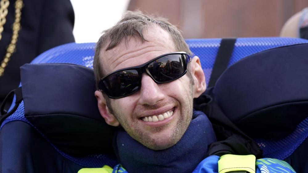 Rob Burrow in dark glasses smiling at the camera