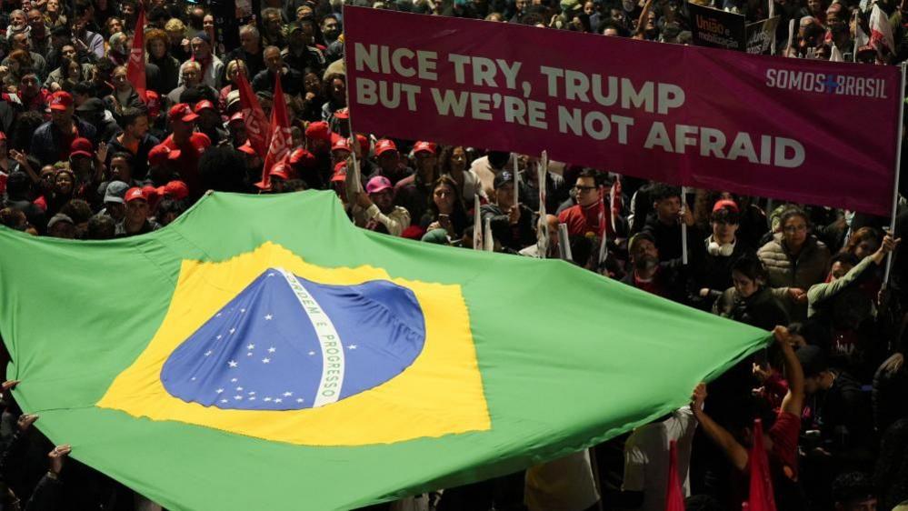 People hold a Brazilian flag as demonstrators protest US President Donald Trump's announcement of 50% tariffs on Brazilian products, in Sao Paulo, Brazil, on July 10, 2025.