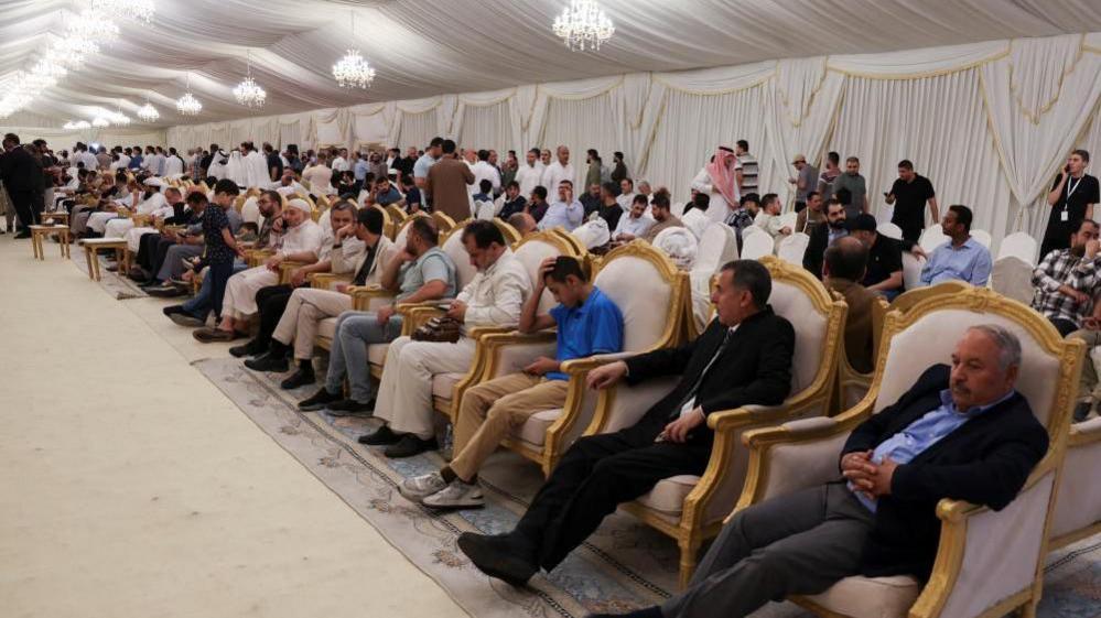 Hundreds of men mourning Haniyeh pictured sitting in ornate chairs in Doha