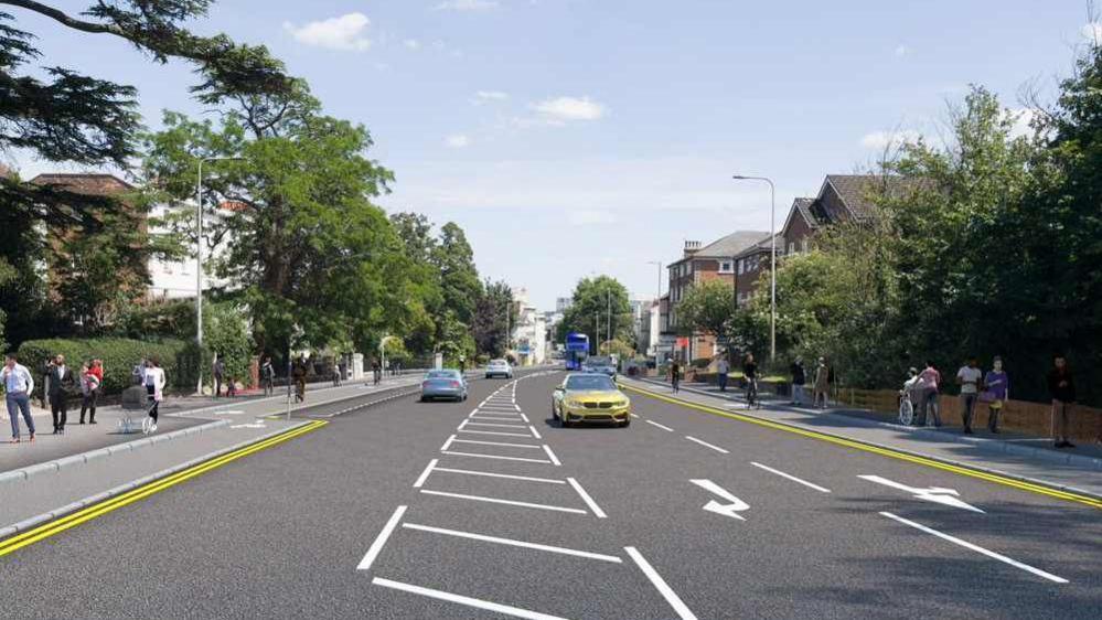 A computer generated image showing a three-lane road with a segregated cycle lane on each side. There are cyclists using the cycle lane and pedestrians walking along the pavement. There are trees on either side and it's a sunny day.