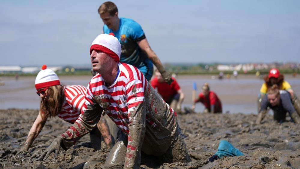 Competitors take part in the annual Maldon Mud Race, a charity event to race across the bed of the River Blackwater in Maldon, Essex