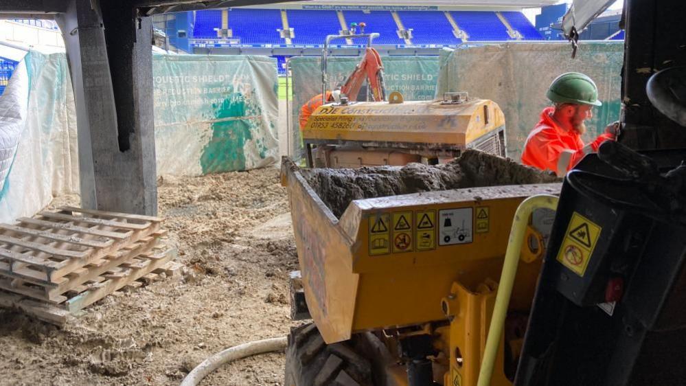 Workman and machine in the stands on ground level