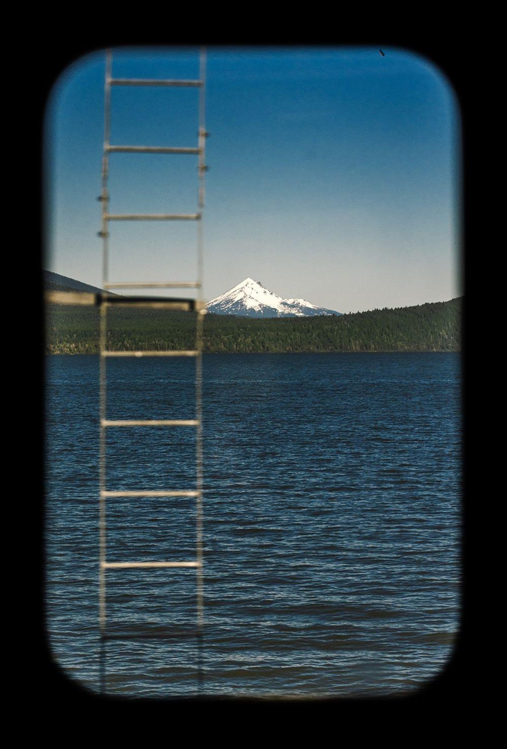 A ladder coming out of a lake in front of snow capped mountains