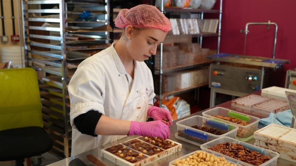 Chocolate worker adds nuts to bars of chocolate