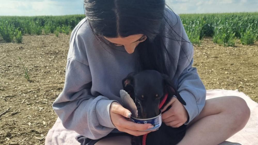 Mila eating out of tin while being held by her owner