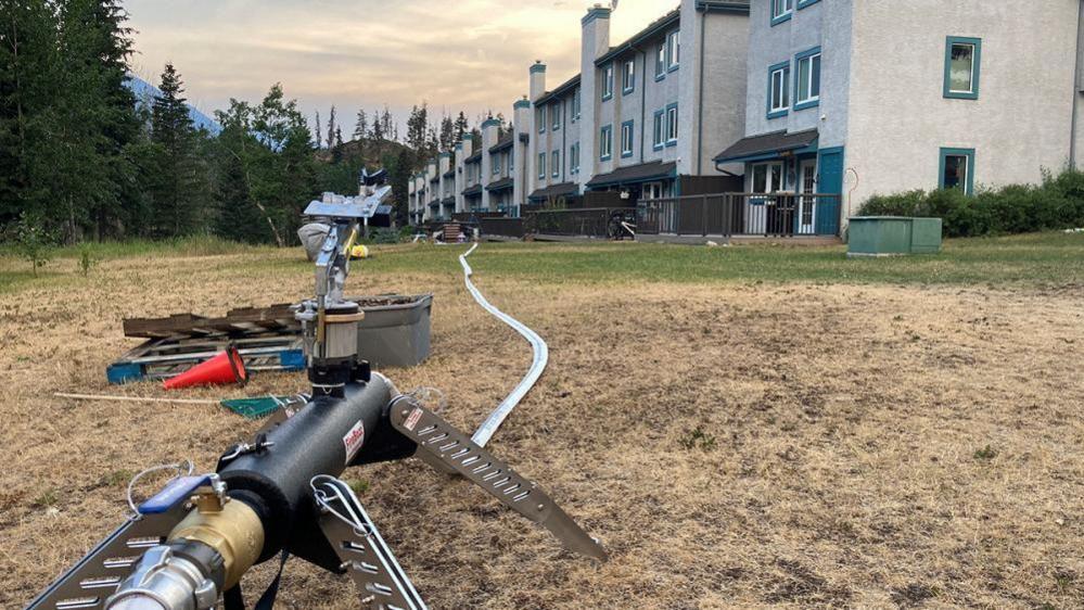 A water hose for structural protection is set up near housing in the Rocky Mountains village of Jasper, Alberta, Canada