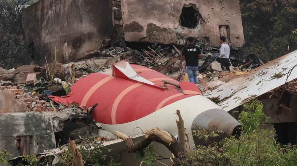 Image shows two officials inspecting the site of an airplane crash near Sardar Vallabhbhai Patel International Airport in Ahmedabad, Gujarat, western India