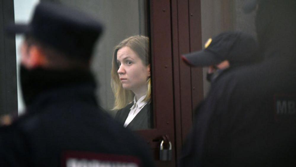 Darya Trepova stands in a courtroom in St Petersburg surrounded by Russian police during her trial in 2023