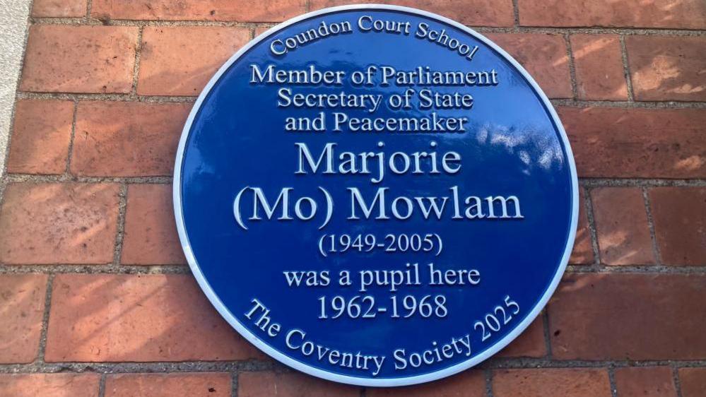 A blue plaque on a red brick wall reads: Coundon Court School. Member of Parliament, Secretary of State and Peacemaker Marjorie (Mo) Mowlam (1949-2005) was a pupil here 1962-1968. The Coventry Society 2025.