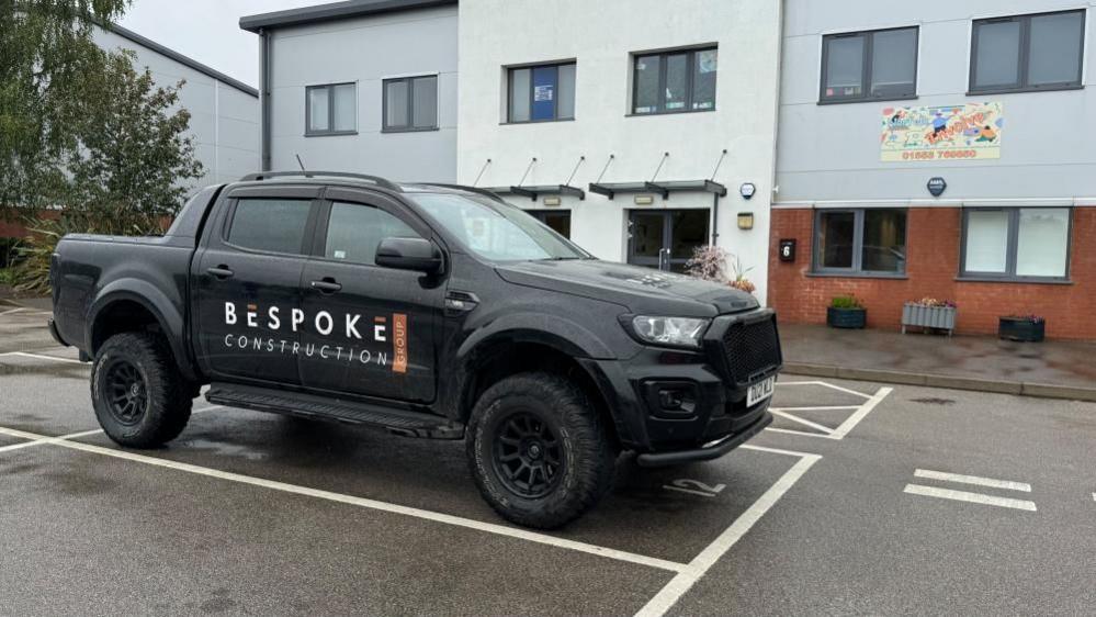 A black 4x4 truck, branded Bespoke Construction Group, parked outside the offices of the company.