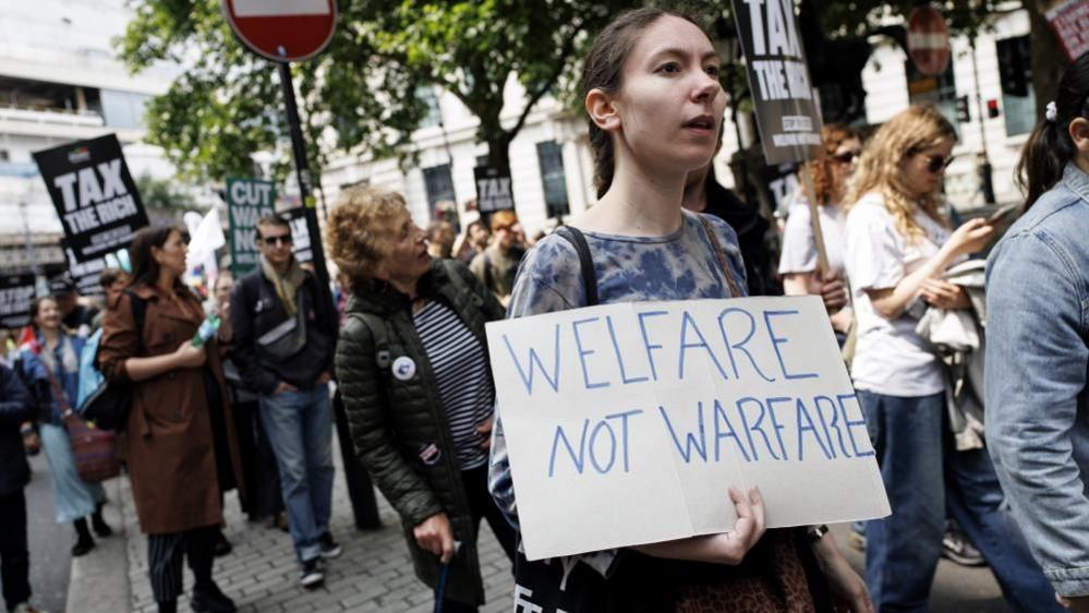 Anti-austerity campaigners carry placards as they march from Portland Place to Whitehall during the People's Assembly national protest in central London, Britain, 07 June 2025