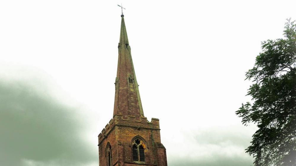 Church spire next to dark cloud