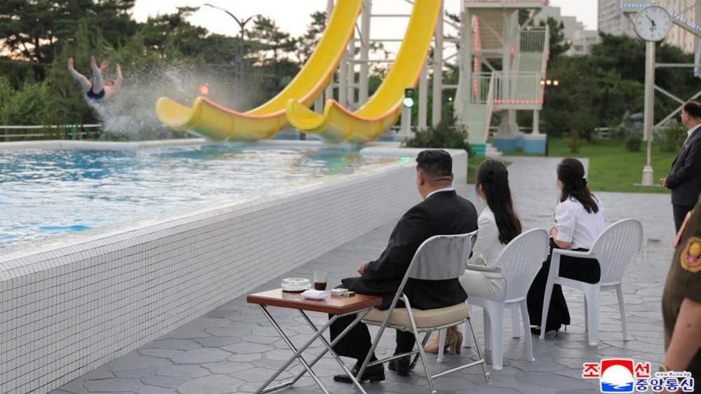 North Korean leader Kim Jong Un, his daughter Kim Ju Ae and his wife Ri Sol Ju watch a person sliding down a yellow slide at a waterpark in the Wonsan Kalma resort, during a ceremony to celebrate the resort's completion