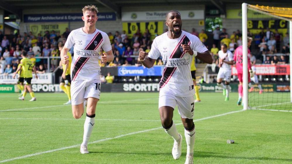 Tendayi Darikwa, right, of Lincoln City, celebrates scoring his side's second goal with teammate JJ McKiernan during the League One match between Burton Albion FC and Lincoln City FC