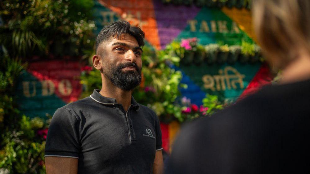 Landscape artist and architect Shiraaz Ali at the Living Wall of Peace next to Laisterdyke Library