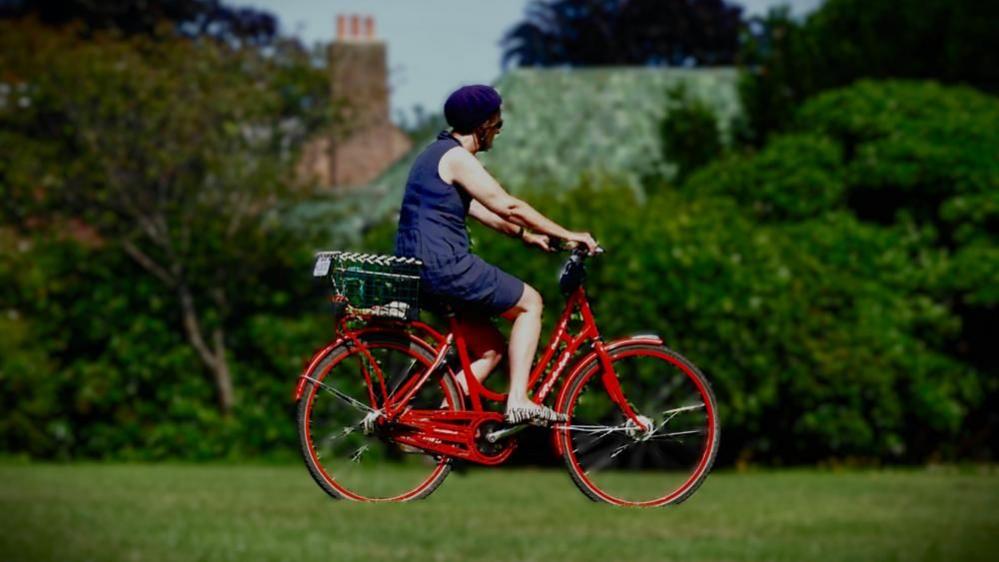 Woman in blue dress on red cycle