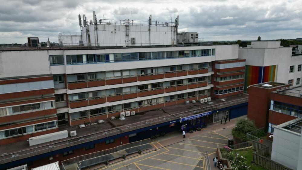 The outside of a five-storey hospital building with white and brown panelling.