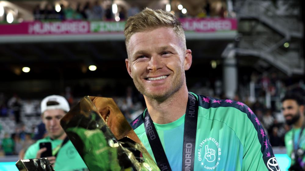 Oval Invincibles captain Sam Billings smiles as he holds up The Hundred trophy
