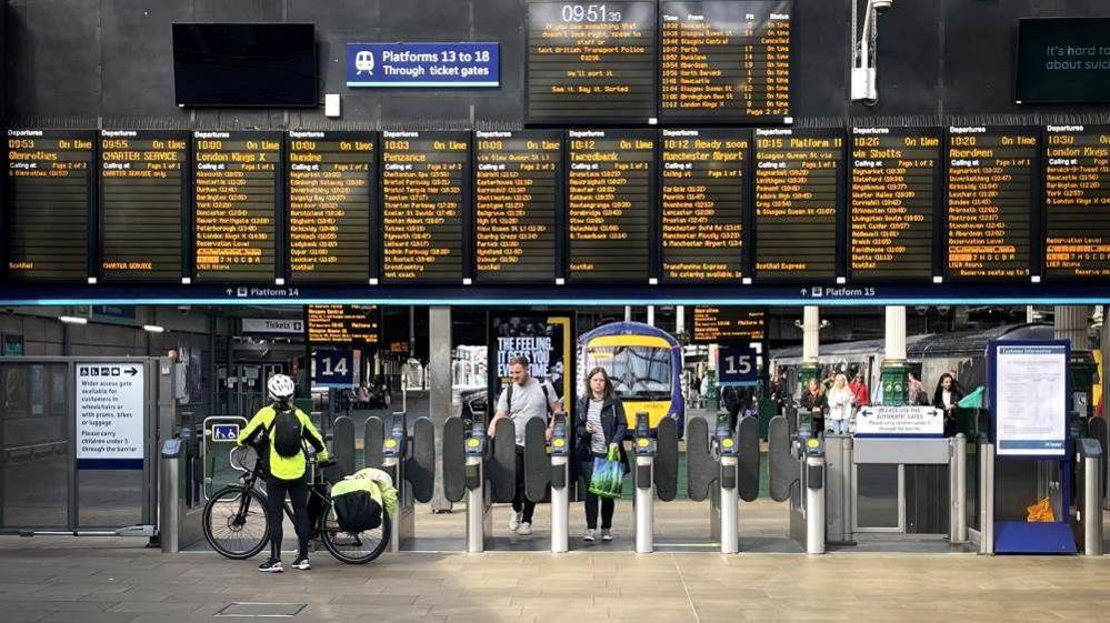 A digital sign in a train station showing the different times of services