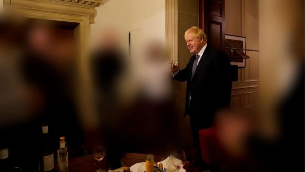 Boris Johnson holds a glass with others blanked out - image from Partygate report