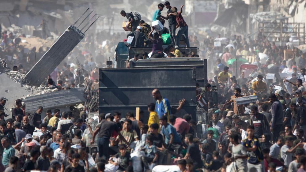 Palestinians take aid supplies from a truck that arrived in Khan Younis in the southern Gaza Strip