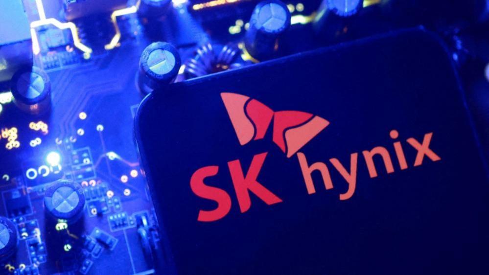 A screen displaying the SK Hynix logo posed above a computing motherboard