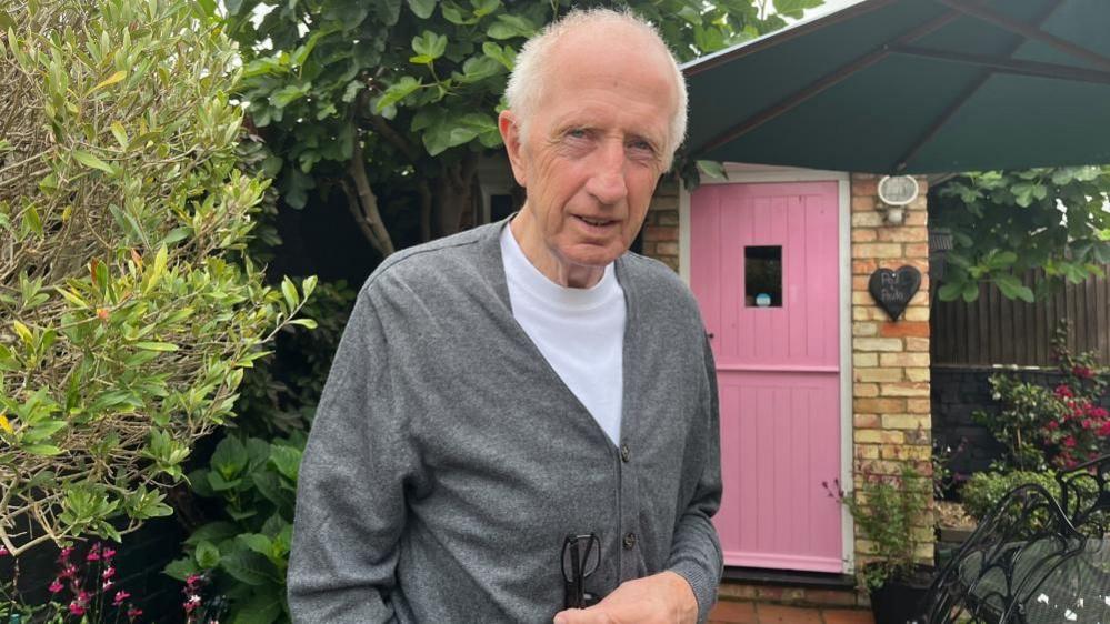 Paul Francis standing in his back garden in front of a pink door