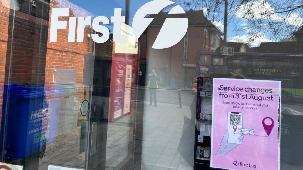 A glass window with the fist bus logo on it and a poster in the corner say Bus routes had changed from 31 August. 
