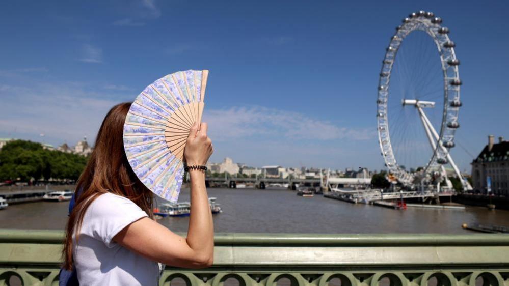 A pedestrian shades herself from the sun on Westminster Bridge in London
