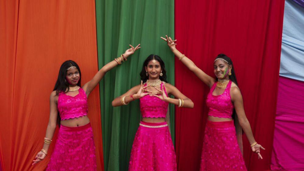 Three women wearing pink traditional attire for the Indian festival Holi pose for a picture - Sunday 9 March 2025.