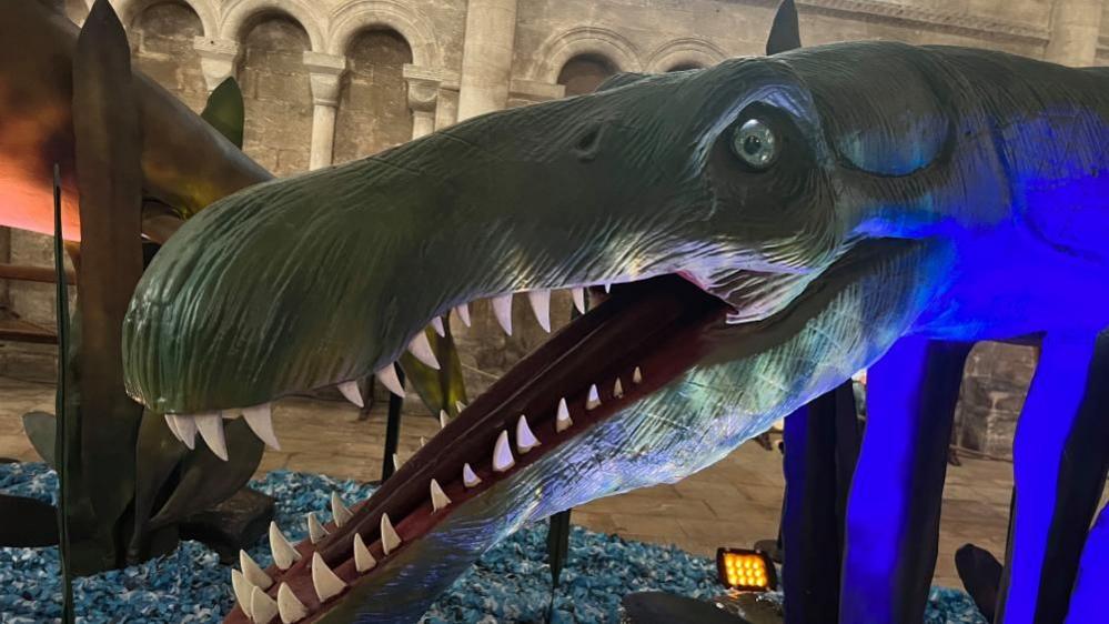 A model of green monster with its mouth open and teeth showing at Peterborough Cathedral.